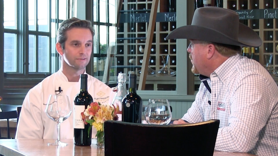 Two men sitting at a table with wine glasses.