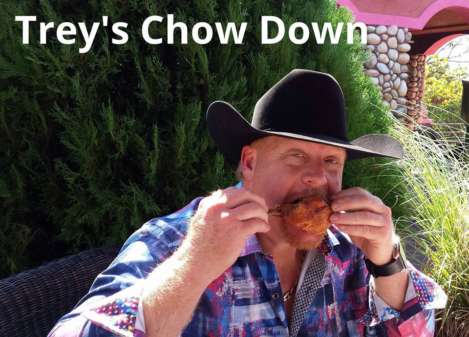 A man in cowboy hat eating food from a donut.