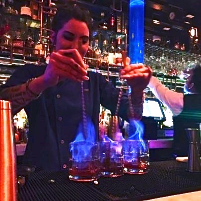 A bartender pouring drinks at the bar.