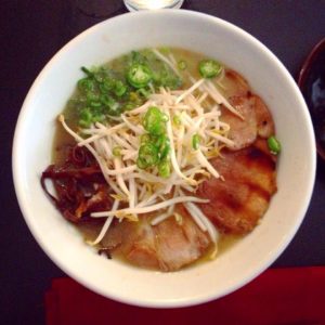 A bowl of soup with broccoli and meat.