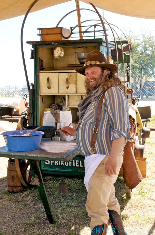 A man standing in front of an old fashioned kitchen.