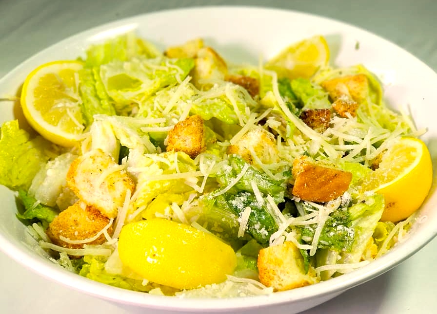 A bowl of salad with lemon and parmesan cheese.