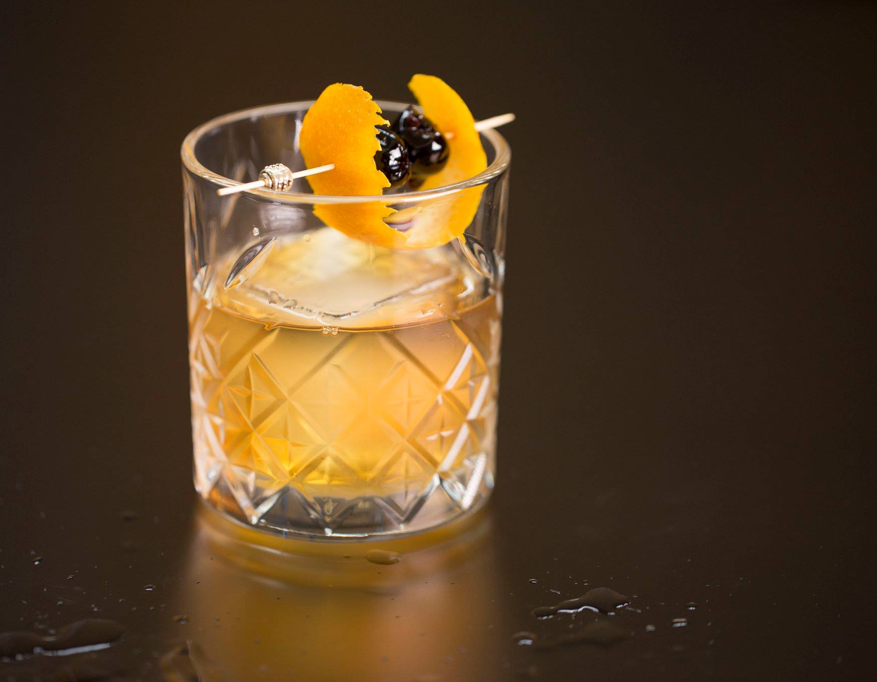 A glass of whiskey with an orange slice on top.