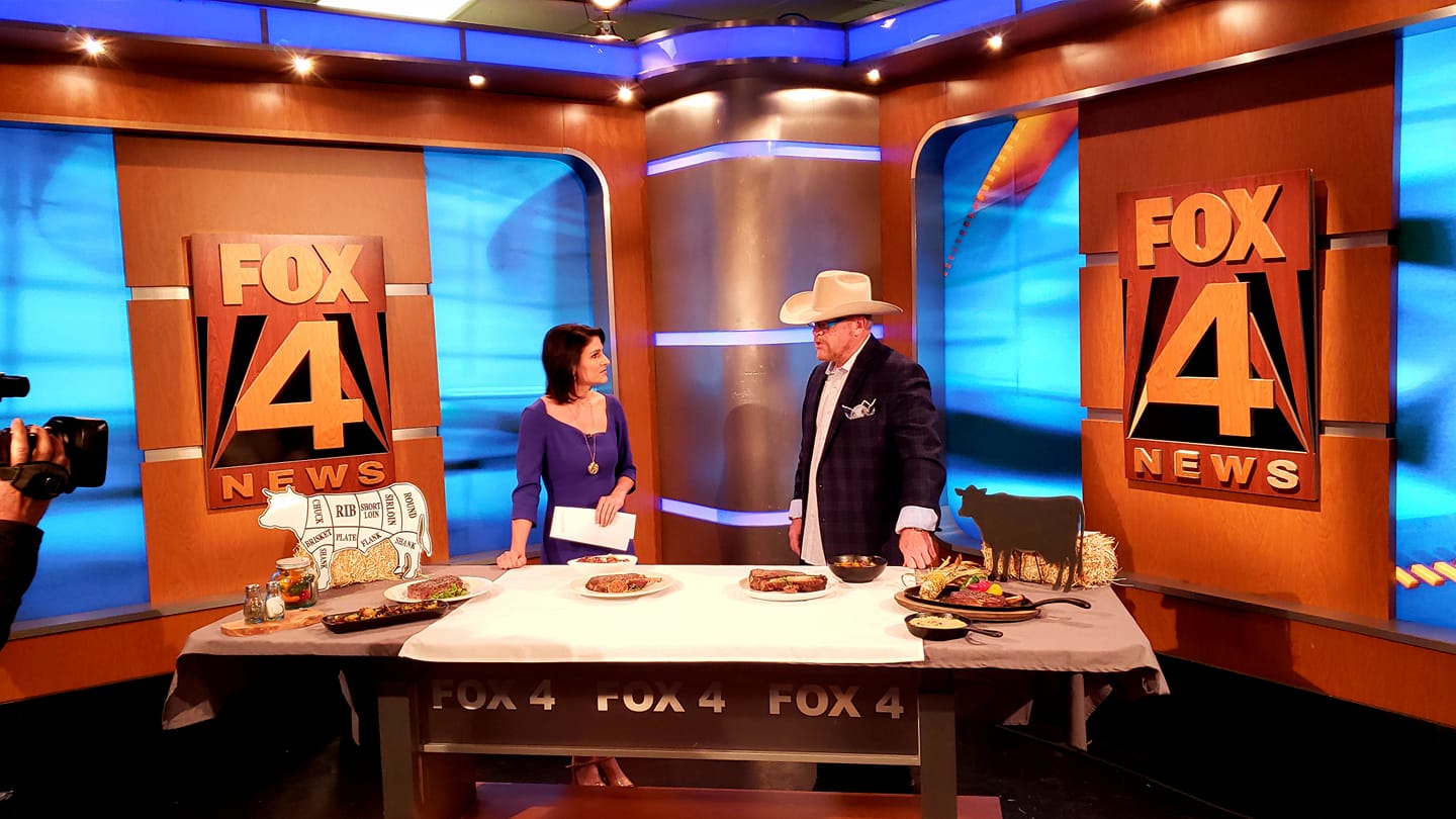 A woman and man standing at a table with food.