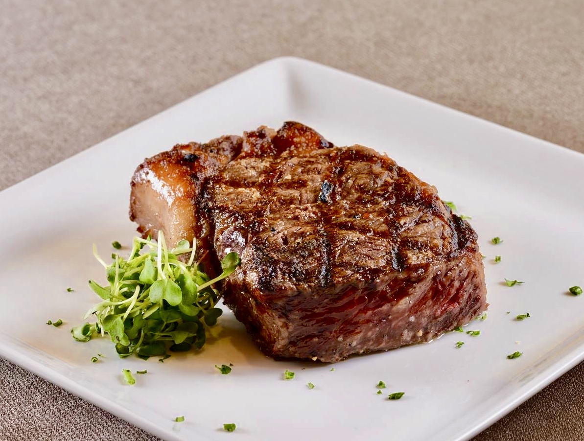 A piece of steak and some green vegetables on a plate.