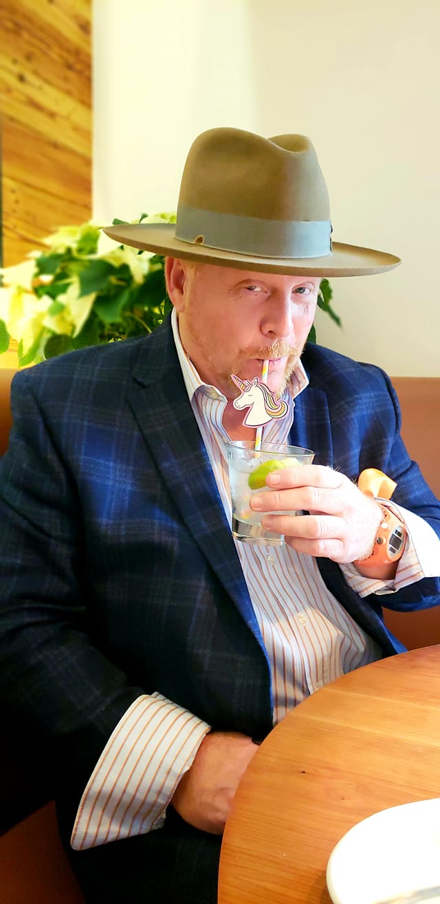 A man in a hat drinking from a glass.