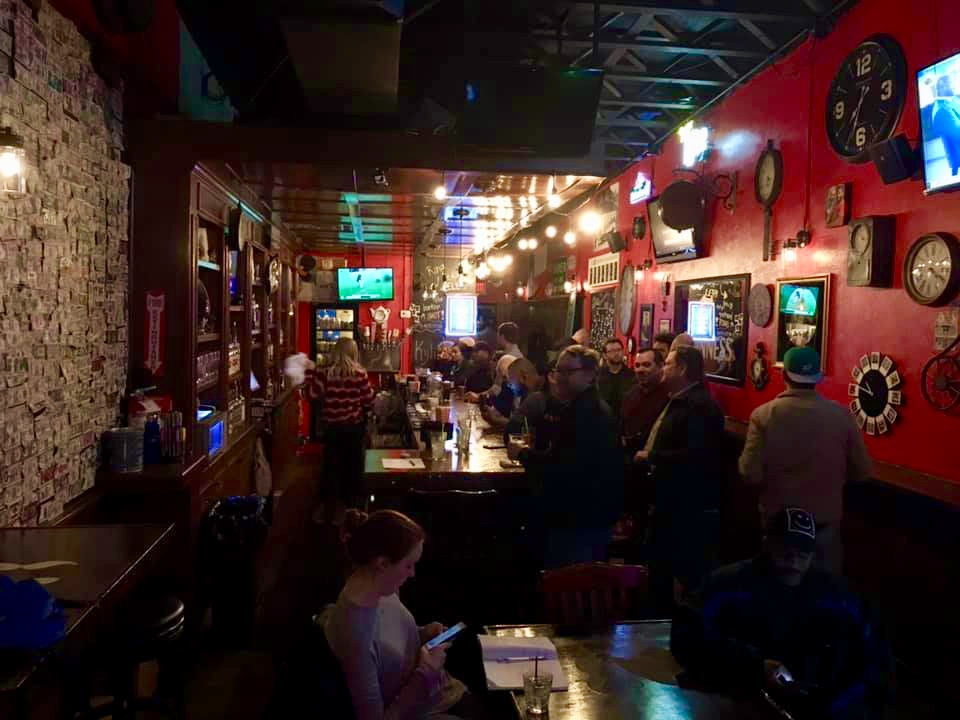 A crowded bar with people sitting at tables.