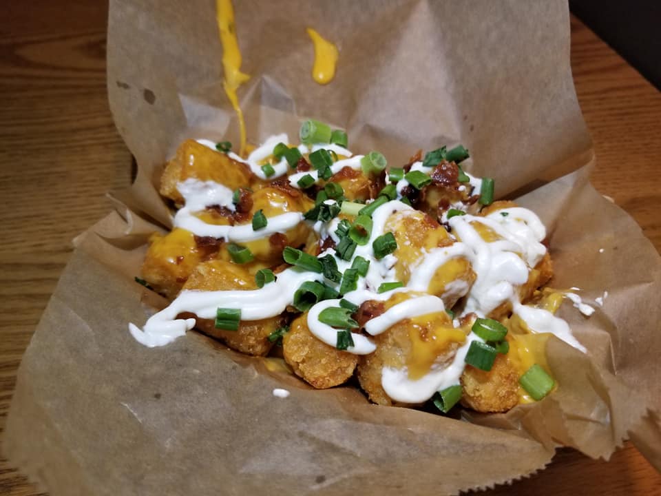 A basket of food with some cheese and green onions.