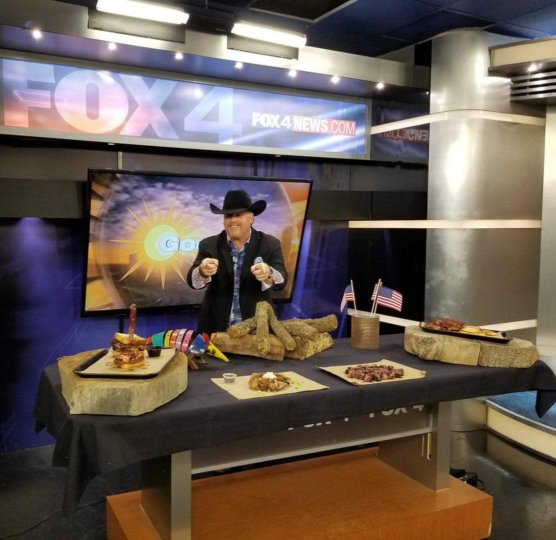 A man in a hat standing at a table with food.