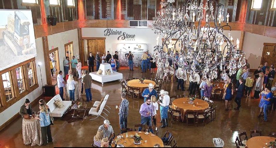 A group of people standing around tables in an event.