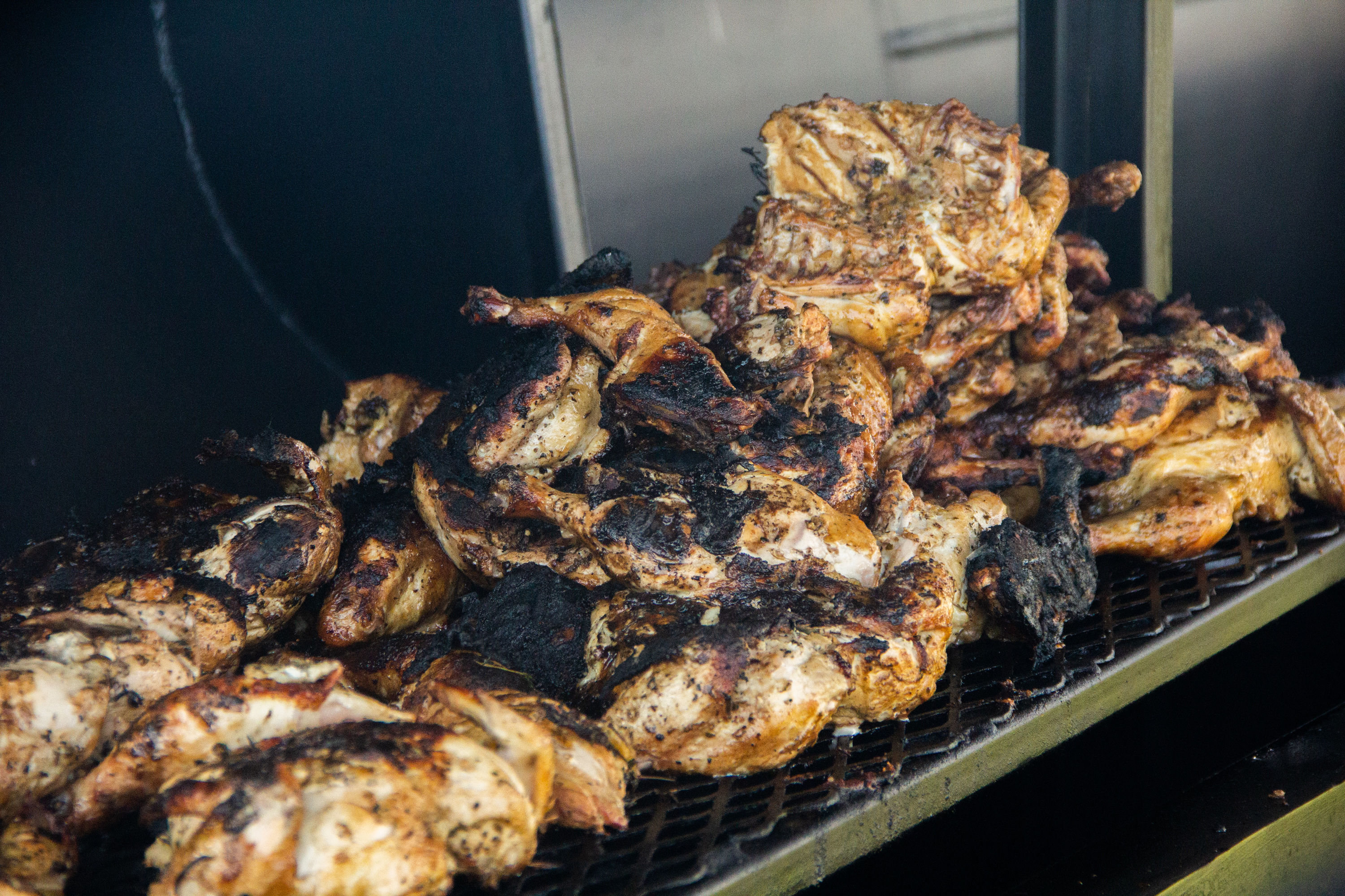 A bunch of chicken is cooking on the grill