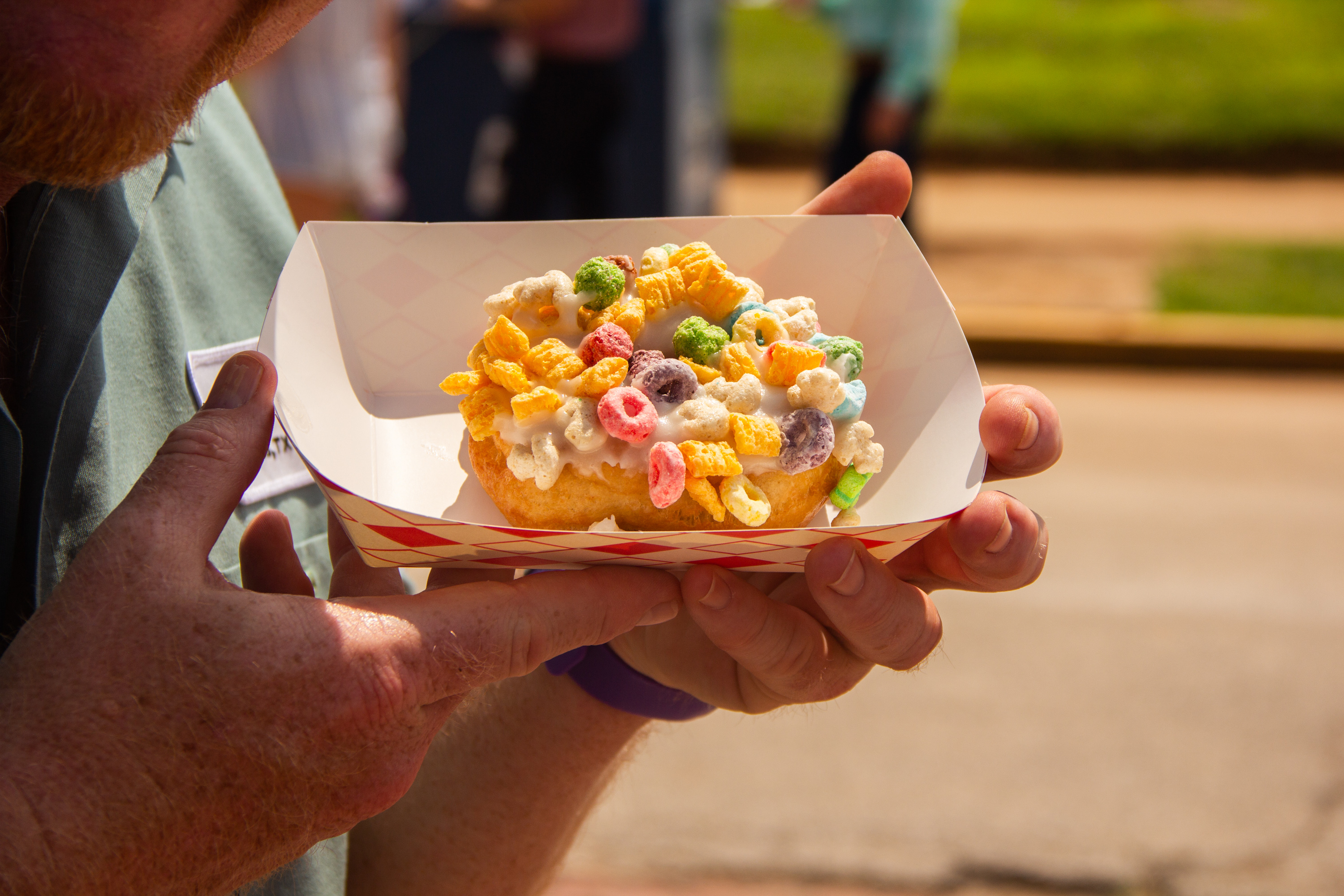 A person holding a paper container with food on it.