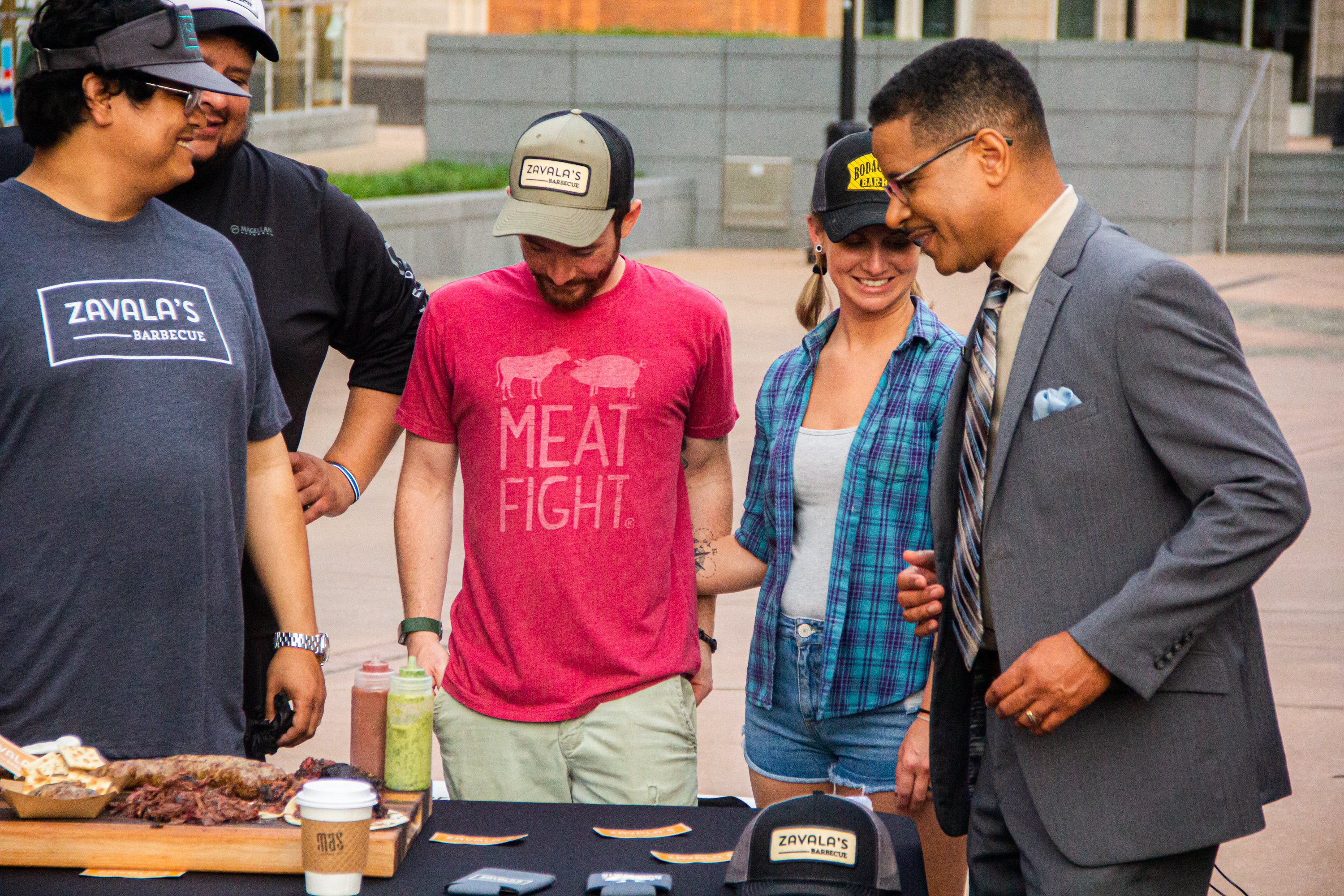 Two men standing next to a table with meat on it.