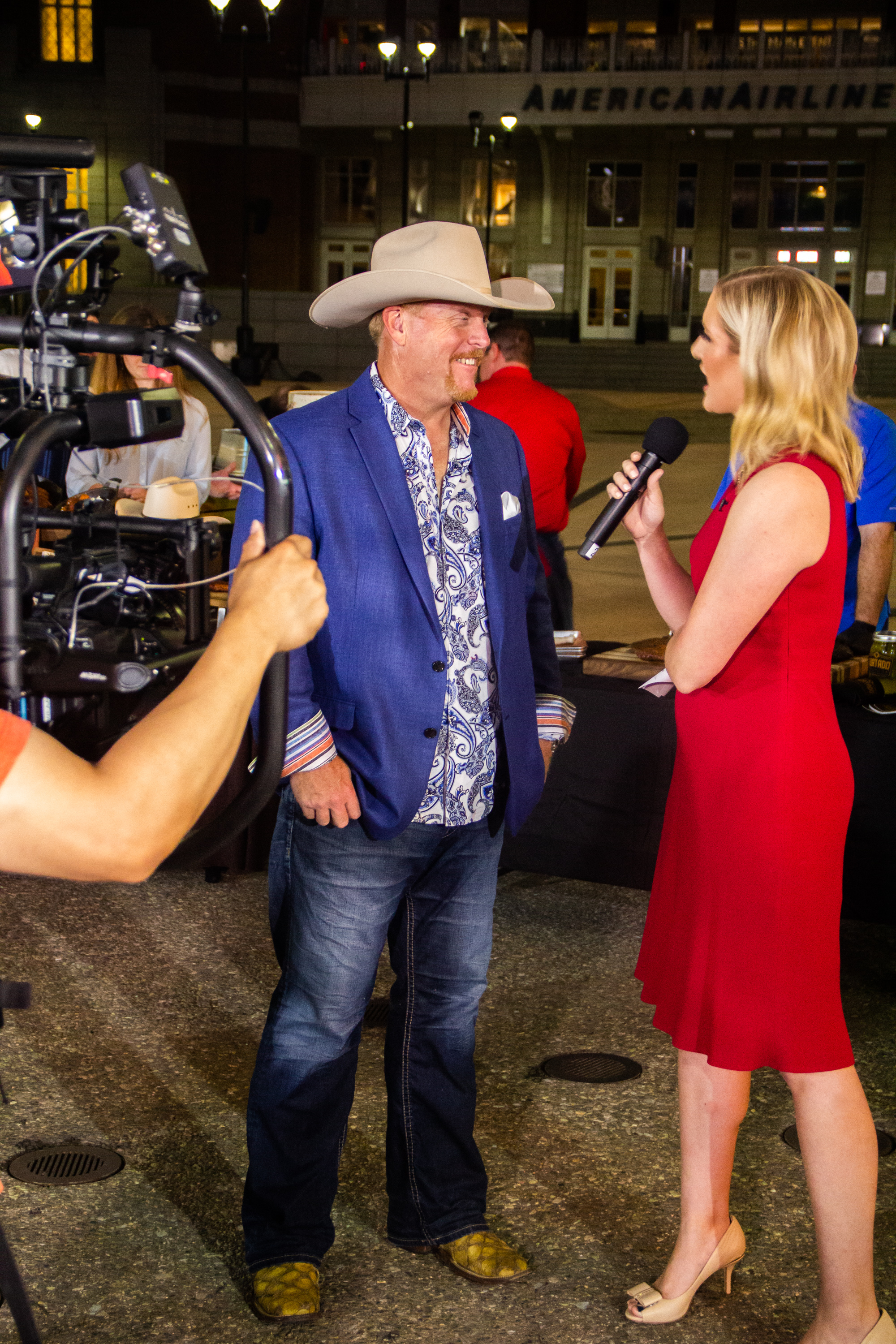 A man in a cowboy hat is being interviewed by a woman.