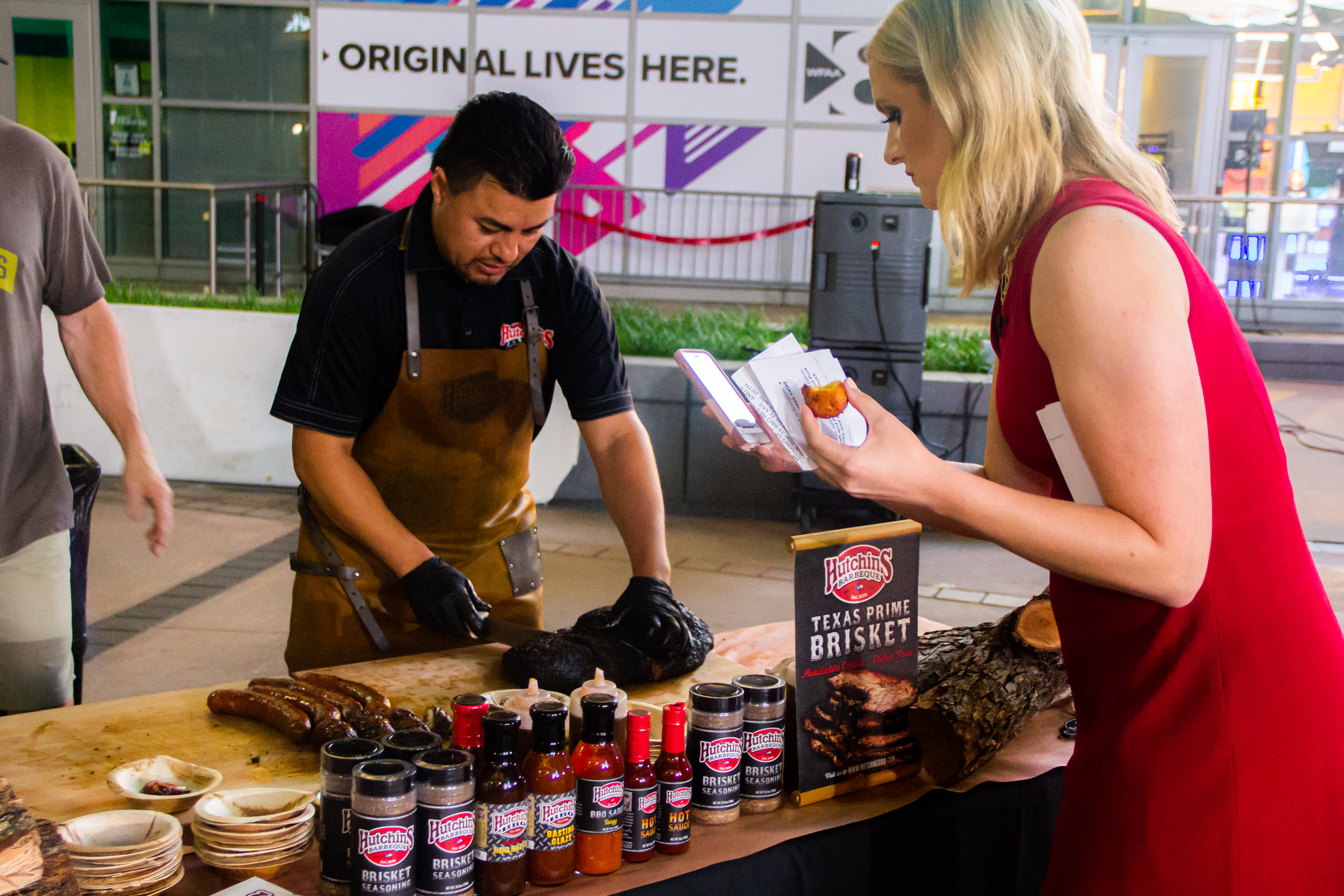 A man and woman preparing food on top of a table.