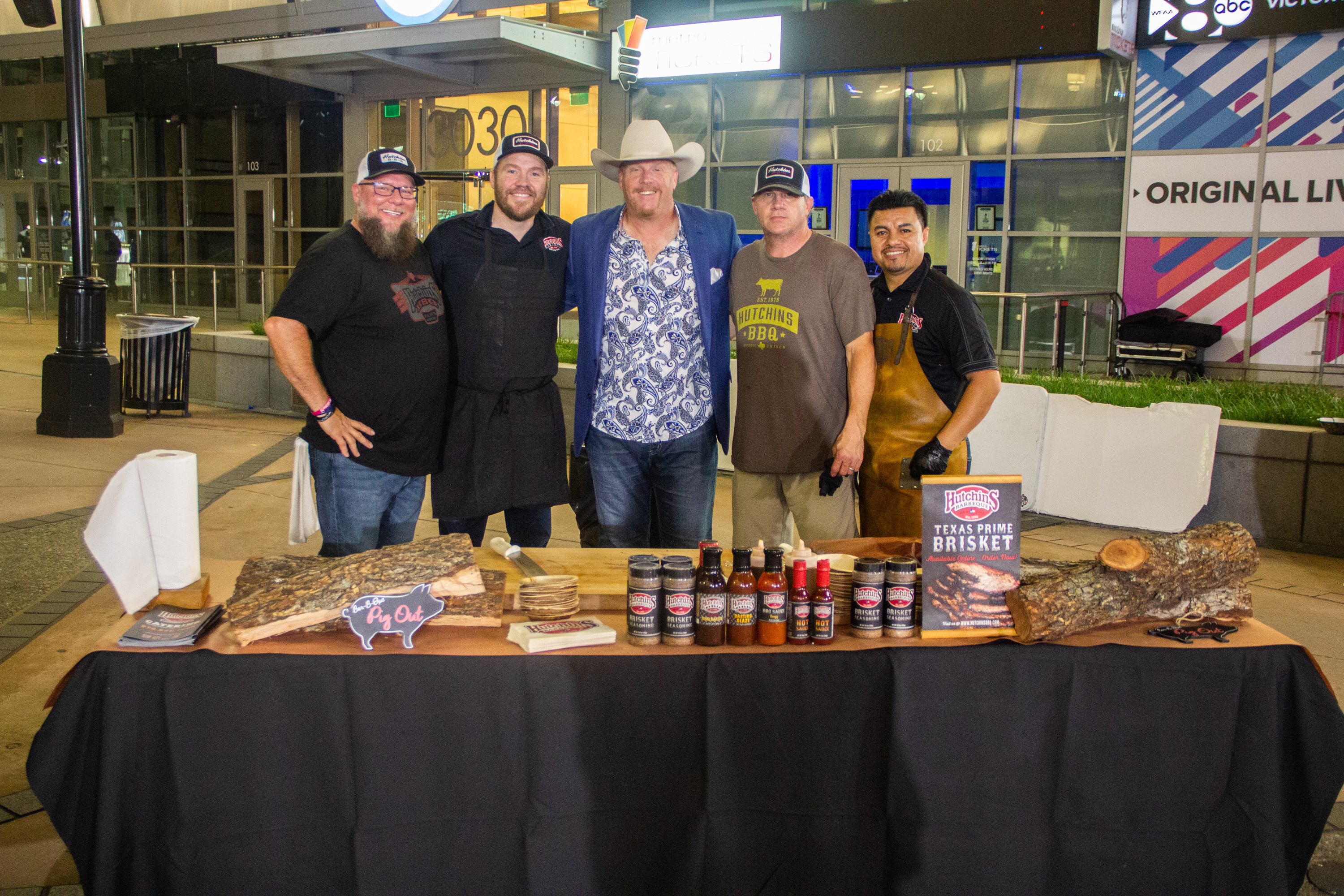 A group of men standing around a table with food.