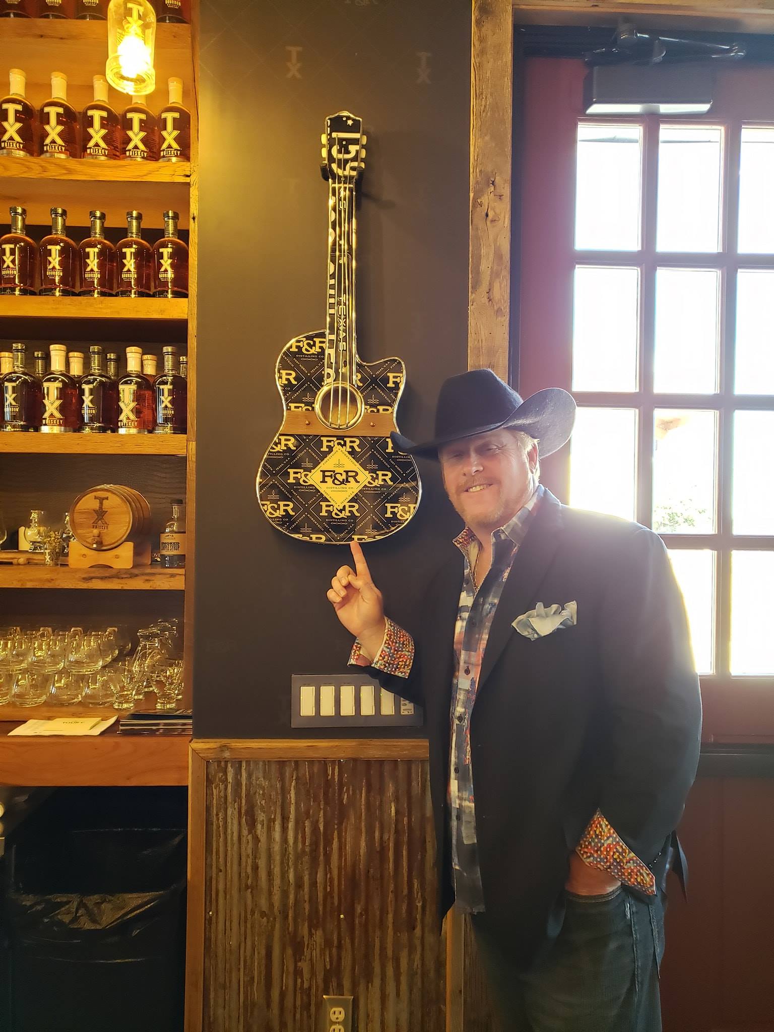 A man in a cowboy hat holding up an instrument.