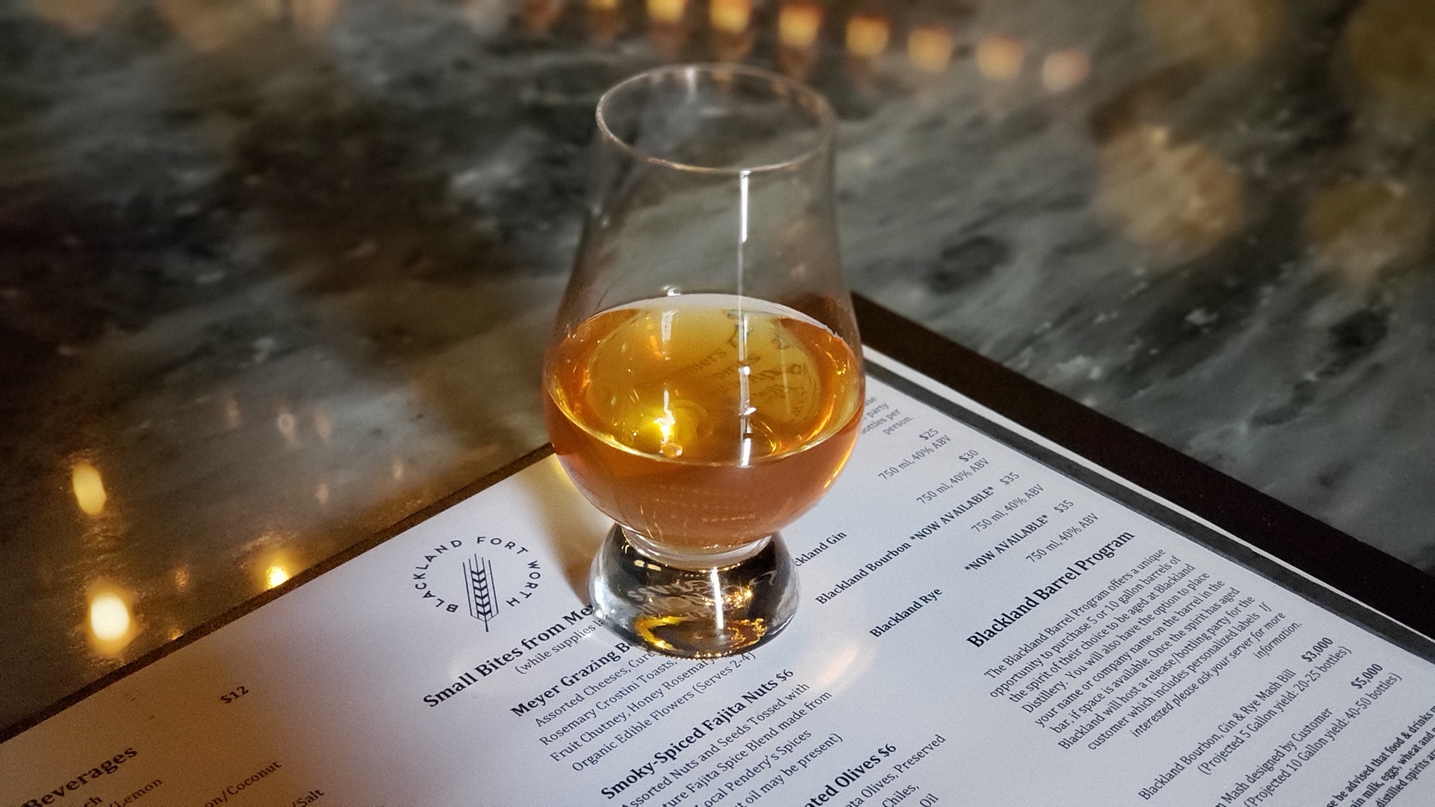 A glass of whiskey on the table at a restaurant.