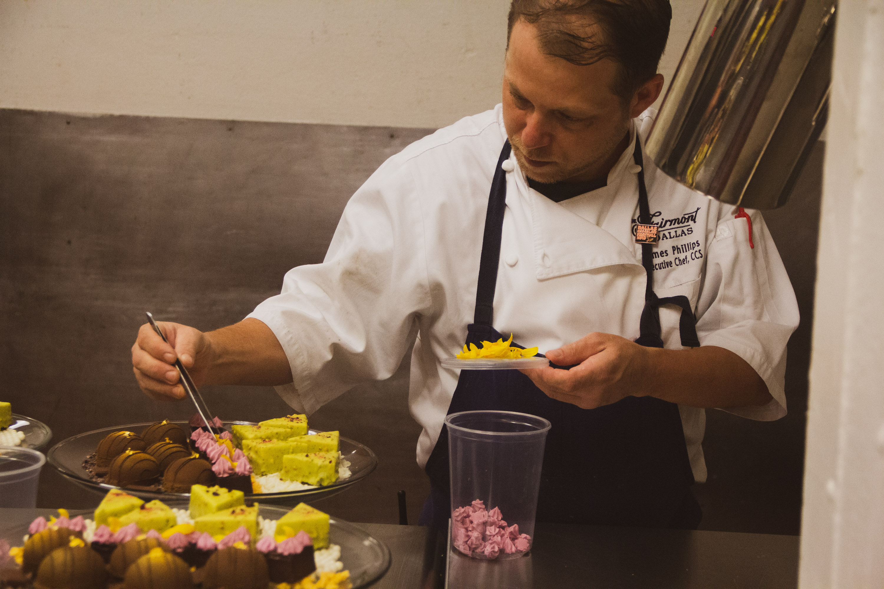 A man in chef 's outfit cutting food on a table.