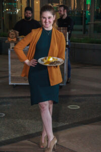 A woman in green dress holding a plate of food.