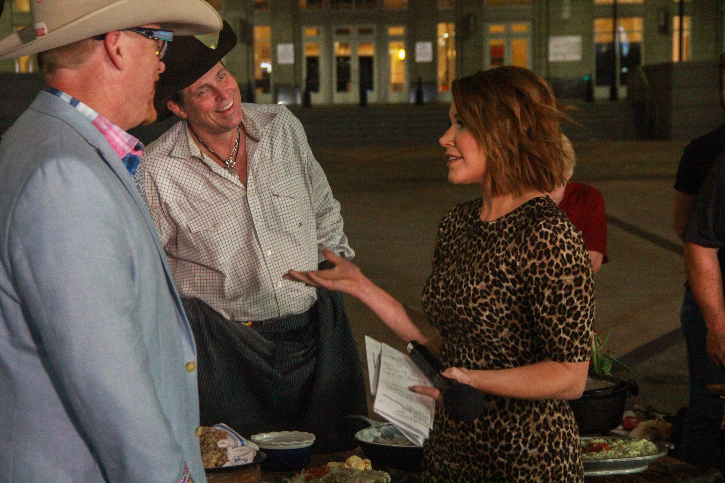 A woman talking to two men in front of a building.