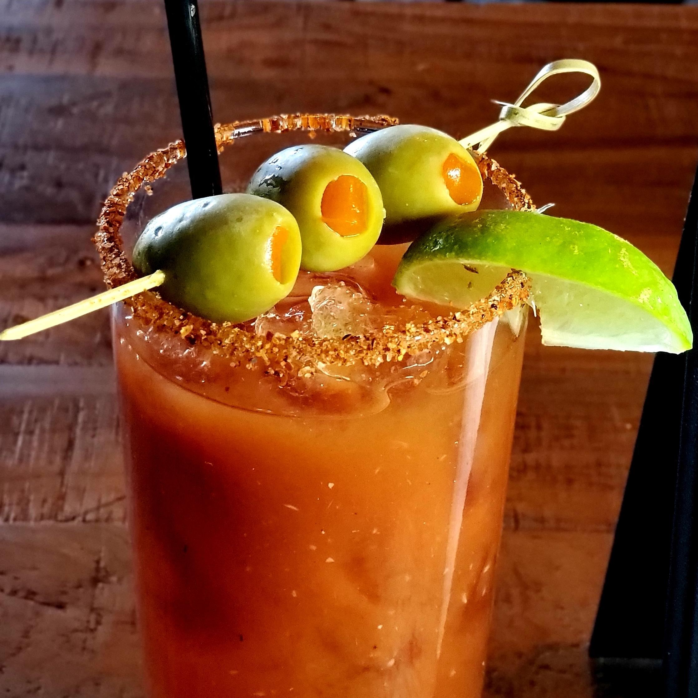 A bloody mary with olives and lime garnish.