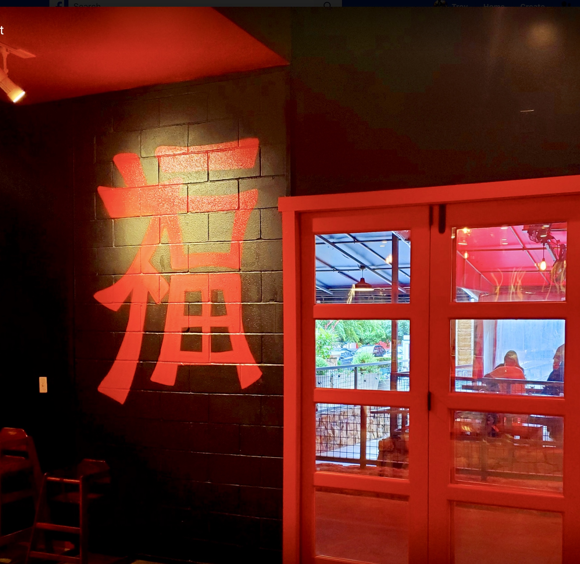 A restaurant with red lighting and chinese characters on the wall.