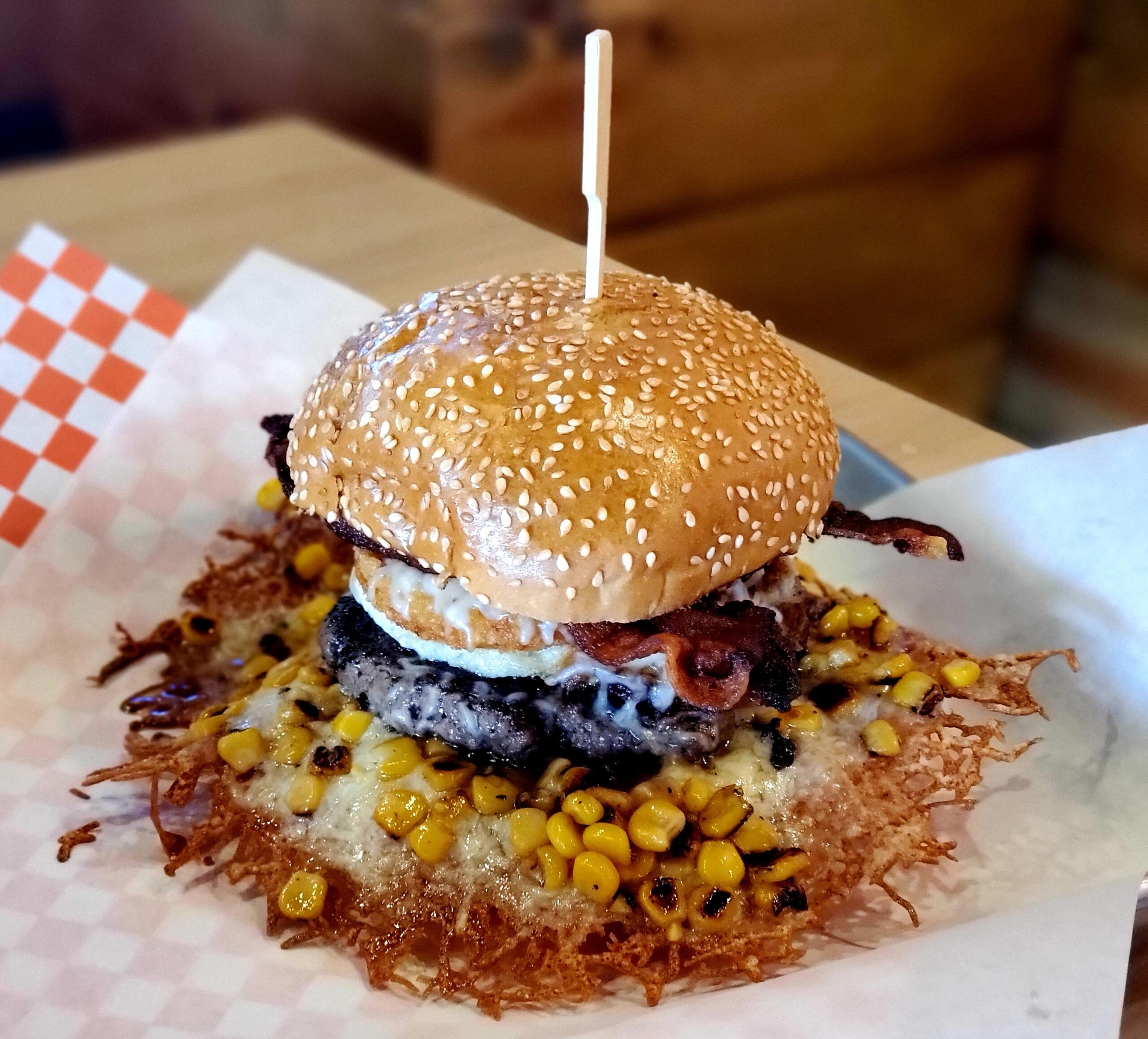 A hamburger sitting on top of some corn.