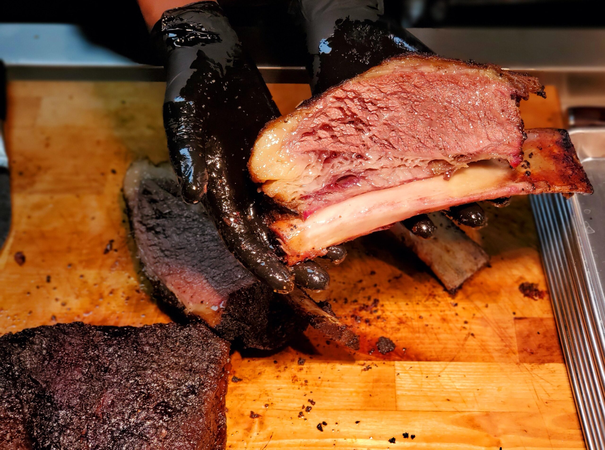 A person wearing black gloves and holding a piece of meat.