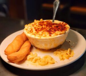 A bowl of macaroni and cheese with fries on the side.