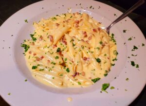 A plate of macaroni and cheese with bacon on top.