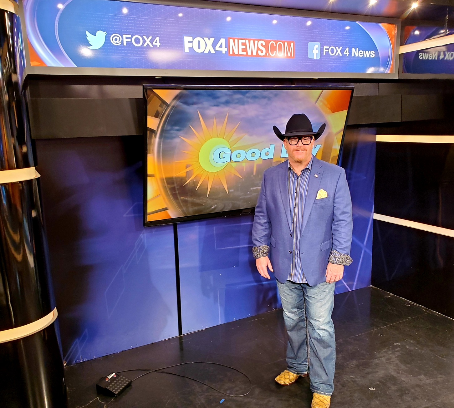 A man in a blue suit and hat standing next to a tv.