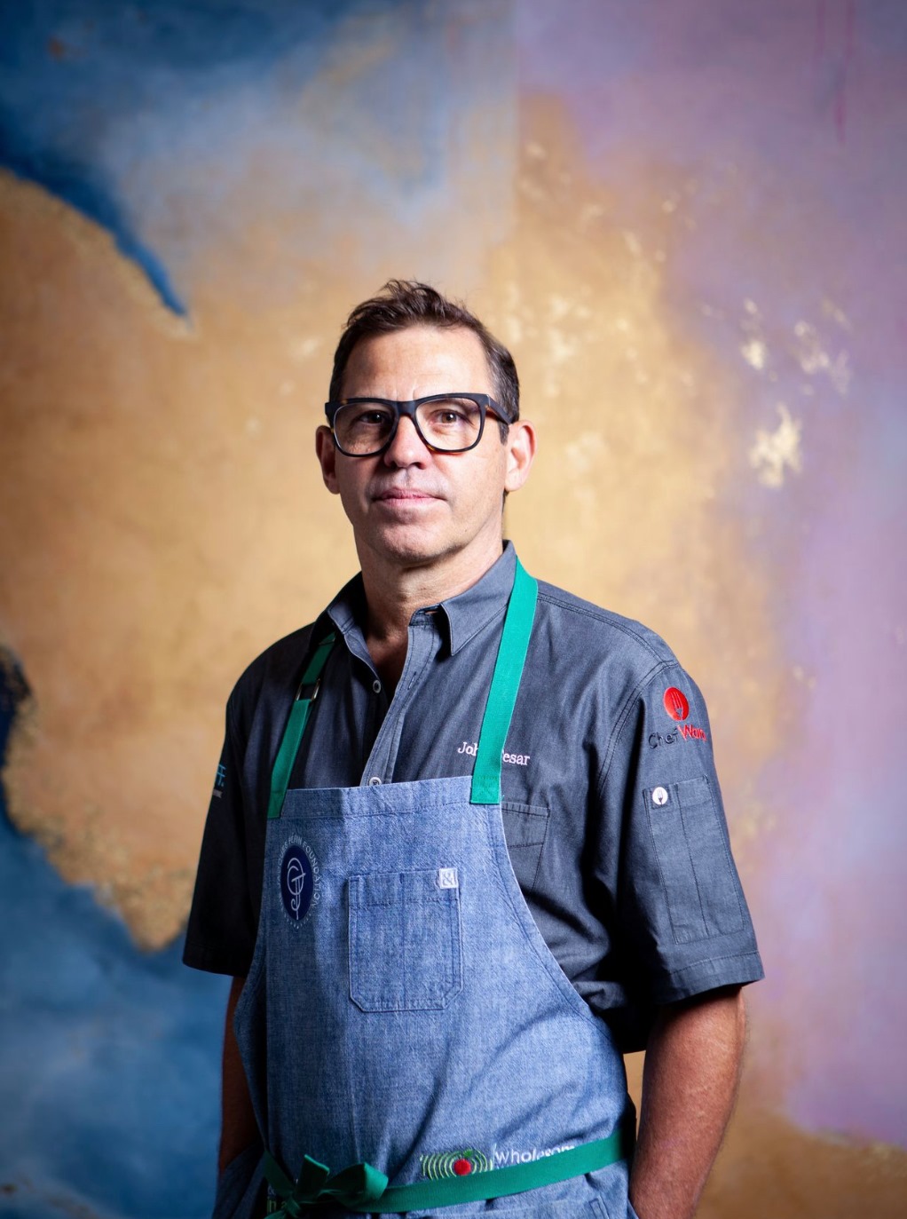 A man in an apron standing next to a wall.