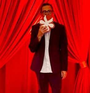 A man holding up a paper flower in front of his face.