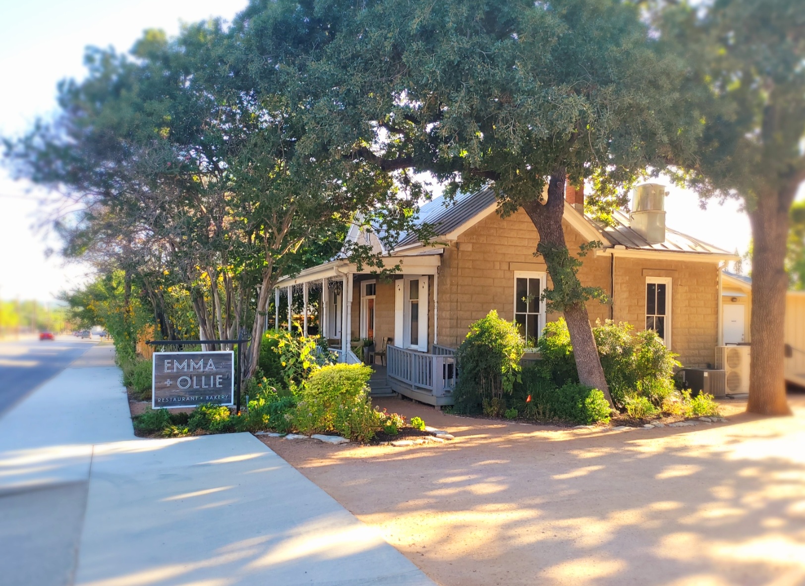 A yellow building with trees and bushes around it.