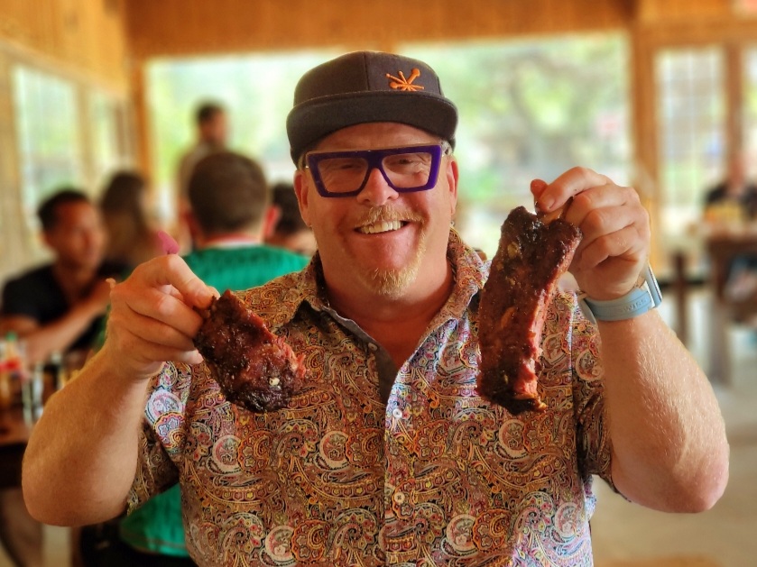 A man holding two pieces of meat in his hands.