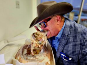 A man in cowboy hat eating food from a box.