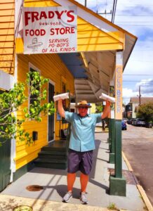 A man standing in front of a store holding up a paper.