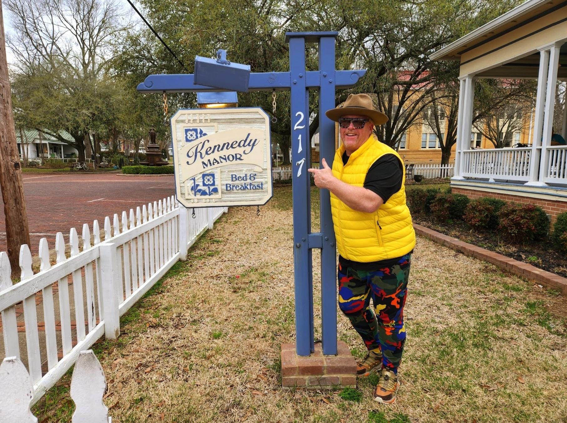 A woman standing next to a wooden sign.