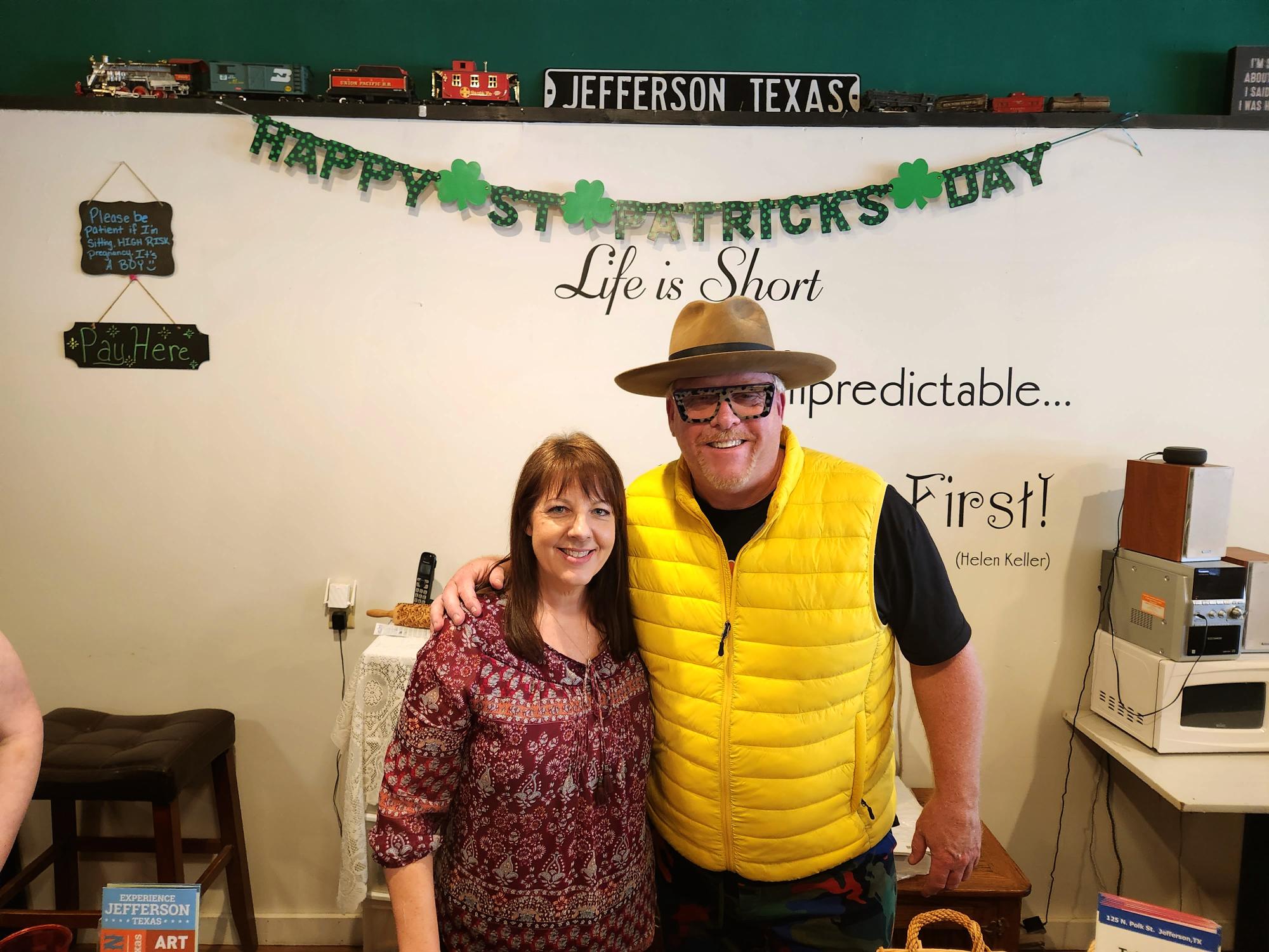 A man and woman standing in front of a st. Patrick 's day sign