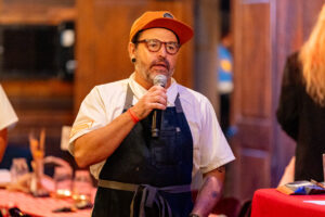 A man in an apron and hat holding a microphone.