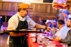 A man serving food to people at an event.