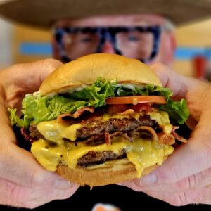 A person holding a hamburger in their hands.