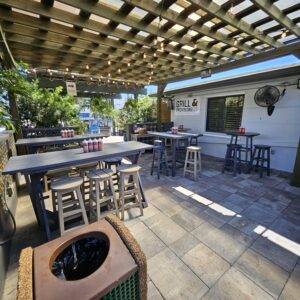 A patio with tables and chairs, air conditioner and grill.