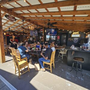 A group of people sitting at tables in an outdoor restaurant.
