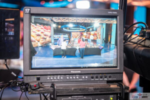 A television set with some people sitting at tables