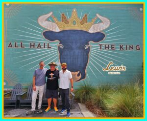 Three men standing in front of a wall with an image of a bull.