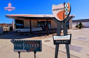 A motel sign in front of an old motel.